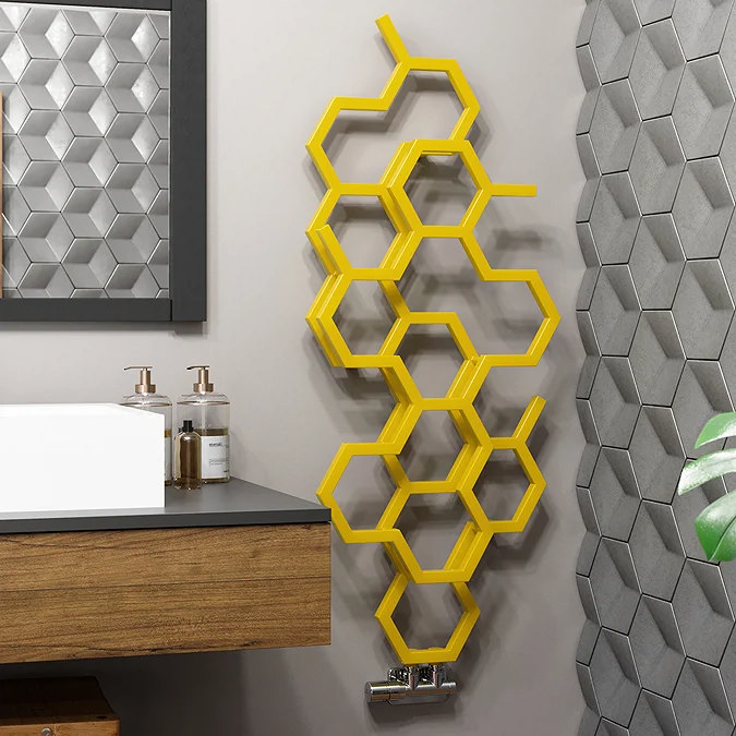 Hexagonal honeycomb-patterned yellow radiator mounted on a bathroom wall, adding a modern and vibrant accent to the space.