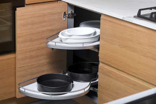 Corner kitchen cabinet with pull-out swivel shelves storing plates and cookware