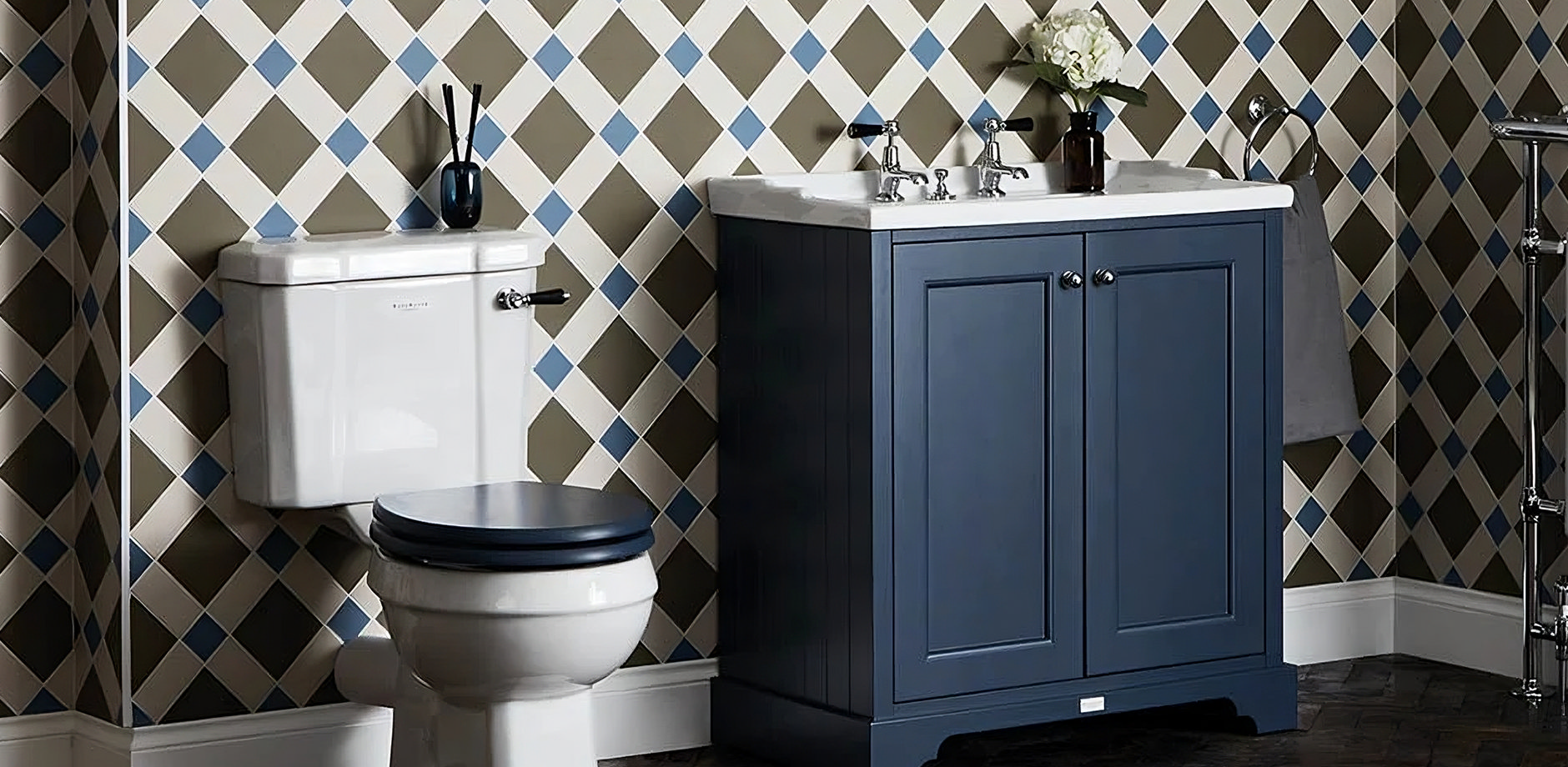 Traditional bathroom with blue vanity unit, classic white toilet, and patterned tiled wall