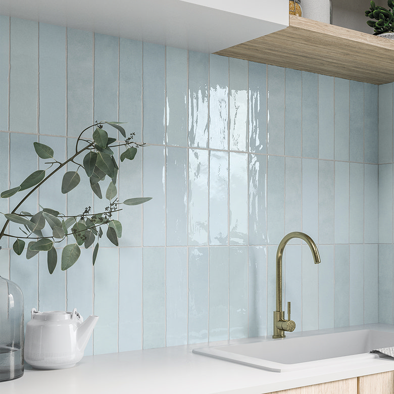 Gloss light blue vertical kitchen tiles with brass tap.