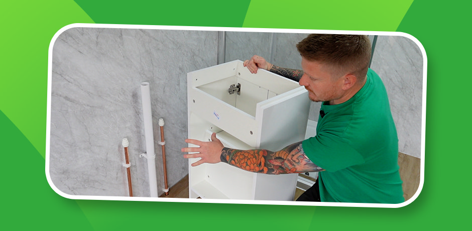 Step 1: installer positions the empty white vanity carcass against bathroom wall to check hot, cold and waste pipe locations