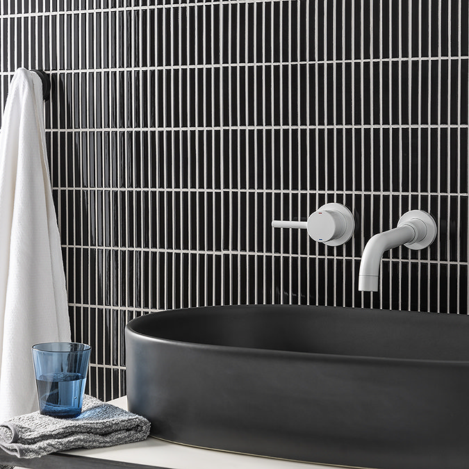 Black vertical kit kat bathroom tiles with a matte black countertop basin and white wall-mounted tap.