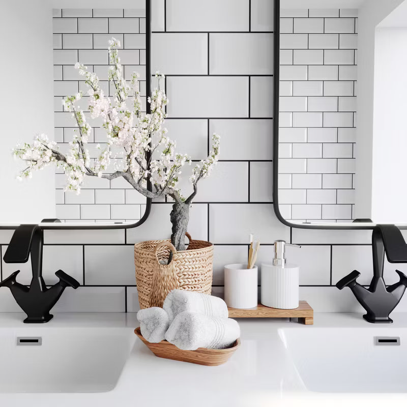 Modern bathroom vanity featuring black-framed mirrors, white subway tiles with dark grout, and a stylish arrangement of decorative items including towels, a wicker basket, and a vase with flowers