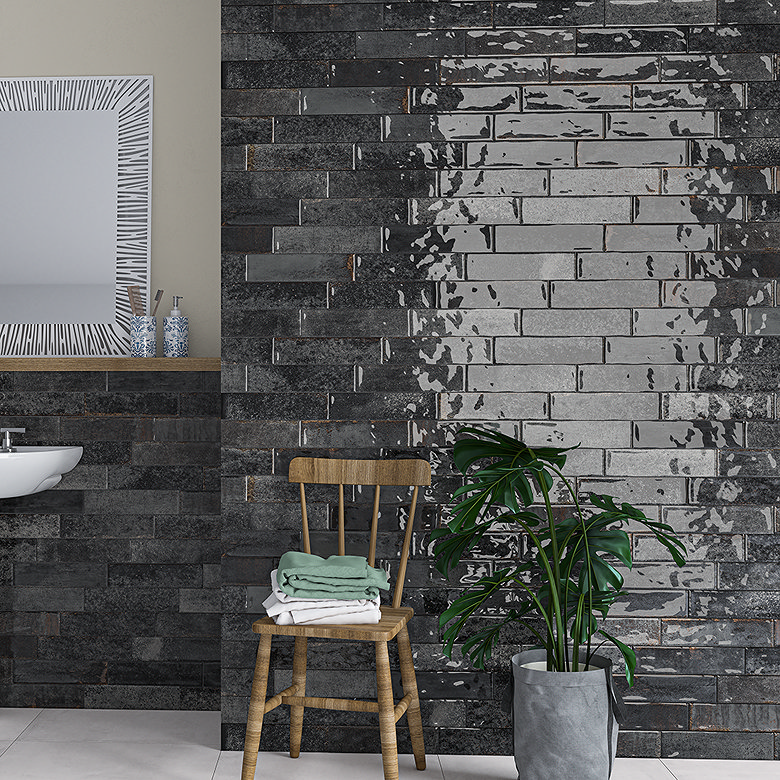 Bathroom with mixed-finish black brick tiles, wooden chair with folded towels, and large potted plant beside a wall-hung basin.