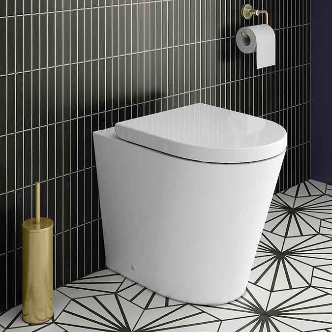 Modern fully shrouded back to wall toilet with sleek design in a small bathroom with black tiles and patterned floor