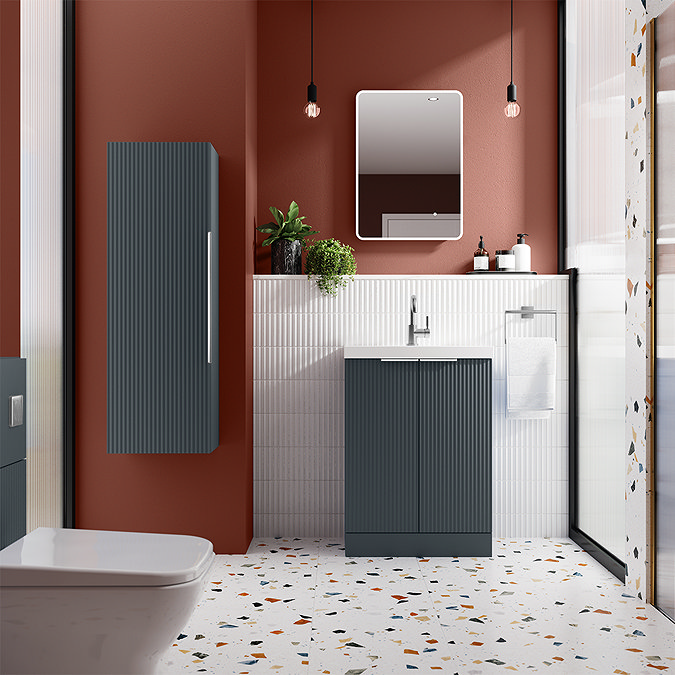 Modern bathroom with fluted dark blue vanity and wall cabinet, against a red accent wall and white tile backdrop, featuring terrazzo flooring, available at Victorian Plumbing