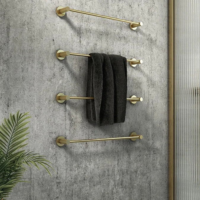 Bathroom wall with gold towel rails holding a dark folded towel against concrete finish