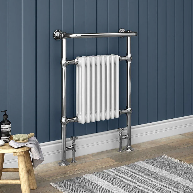 Traditional chrome heated towel rail with white radiator against blue panelled wall