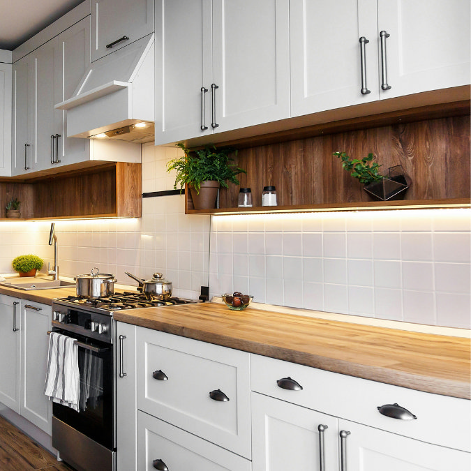 Modern kitchen with white cabinets, wooden worktops, open shelves, and under-cabinet lighting