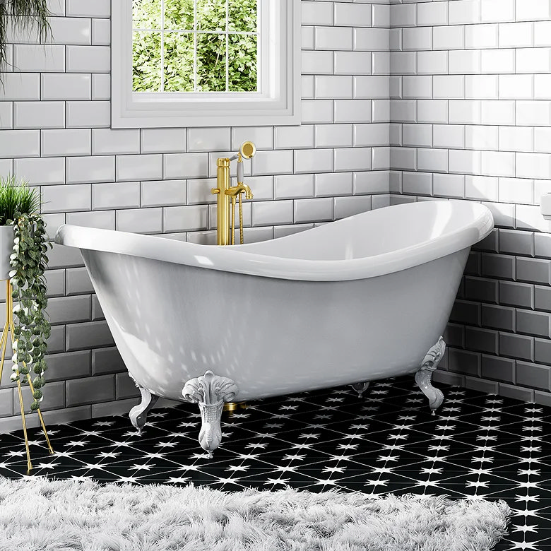 White clawfoot bath with gold taps against grey metro tile walls and black star patterned floor tiles.
