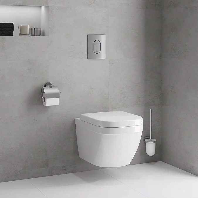 Modern wall-hung toilet in a minimalist grey bathroom with a built-in shelf and chrome flush panel