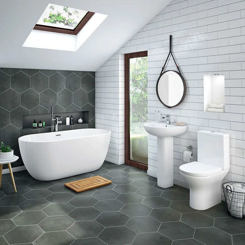 Bright family bathroom with freestanding bath, toilet and pedestal sink on tiled floor