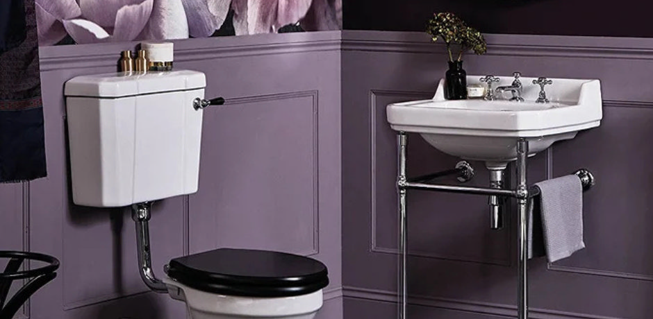 Traditional cloakroom bathroom with purple panelled walls, floral wallpaper, and Victorian-style white basin and toilet – showcasing how deep lilac can elevate small spaces with vintage charm.