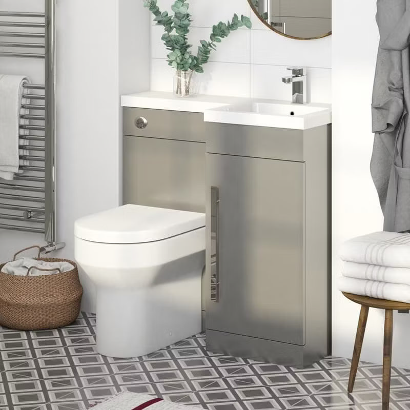 Compact ensuite bathroom with back-to-wall toilet, grey vanity unit, and small basin, featuring geometric floor tiles and a chrome towel radiator.