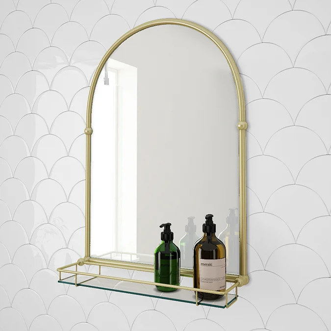Gold framed bathroom mirror with slim glass shelf holding soap dispensers