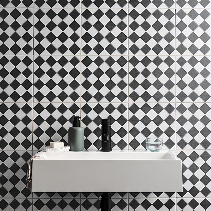 Black-and-white diamond pattern bathroom wall tiles behind a modern floating sink.