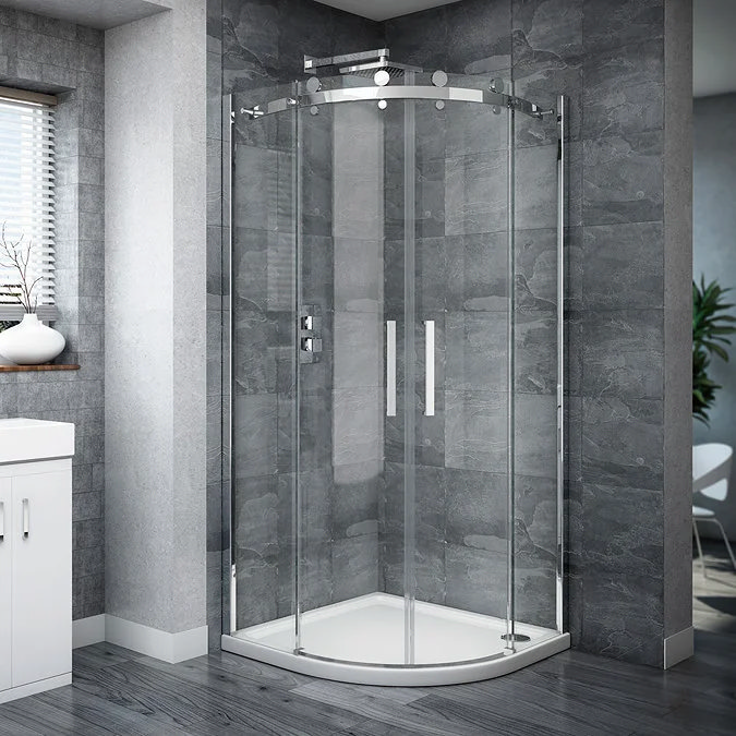 Modern bathroom with a sleek quadrant shower enclosure featuring sliding glass doors and chrome handles, set against grey stone-effect wall tiles for a contemporary, space-saving design.