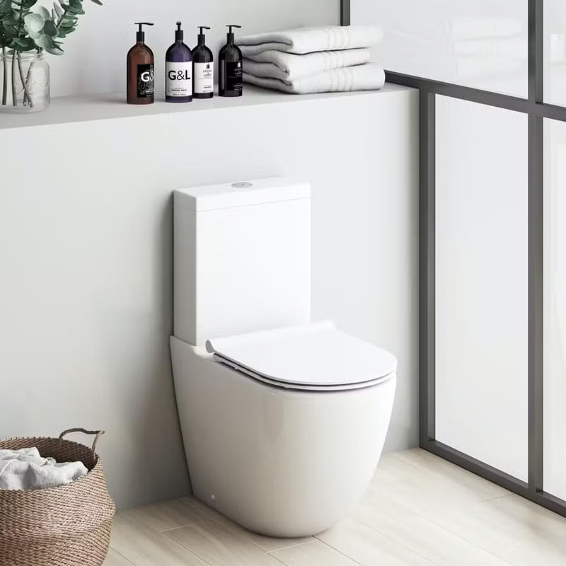 Modern close-coupled toilet in a minimalist bathroom, featuring light wooden flooring, folded towels, and stylish soap bottles for a clean, contemporary look.