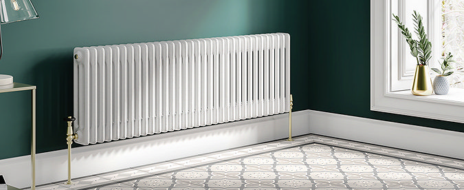 Elegant white traditional 3-column radiator in a classic interior with green walls and patterned floor tiles, combining vintage charm with modern heating efficiency.