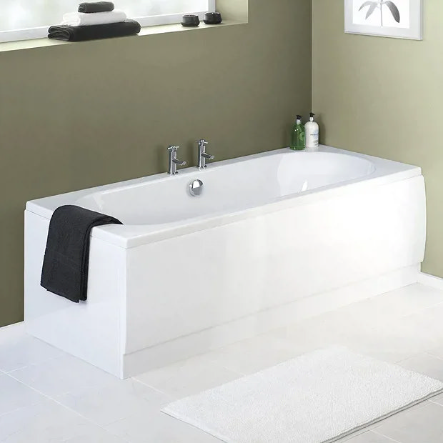 White acrylic bath with a fitted panel in a minimalist bathroom, featuring green walls and tiled flooring, complemented by modern chrome fixtures and a black towel.