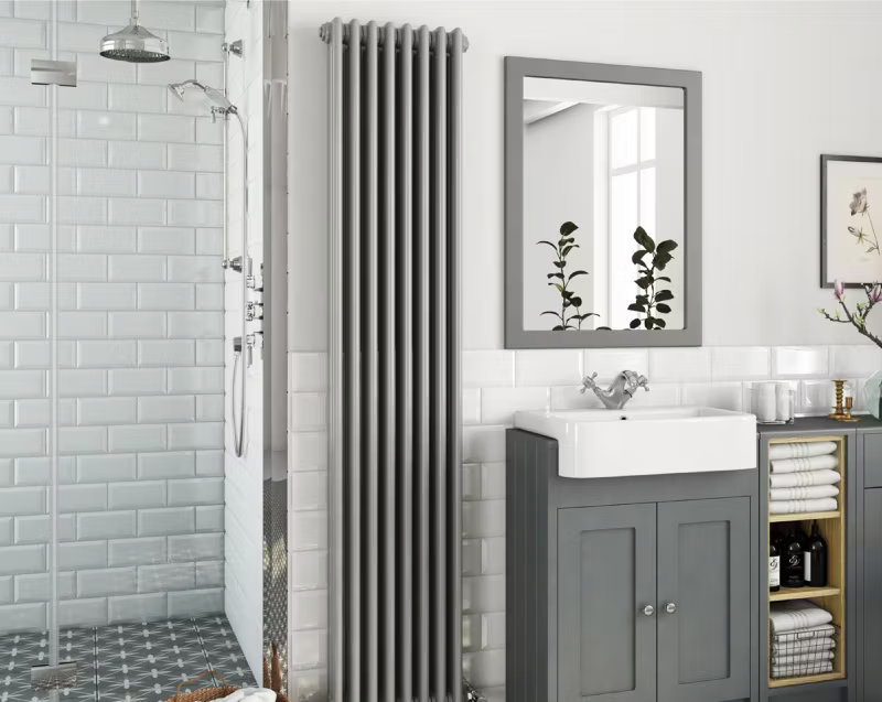 Modern bathroom with tall grey radiator, grey vanity unit, and white subway tile shower area