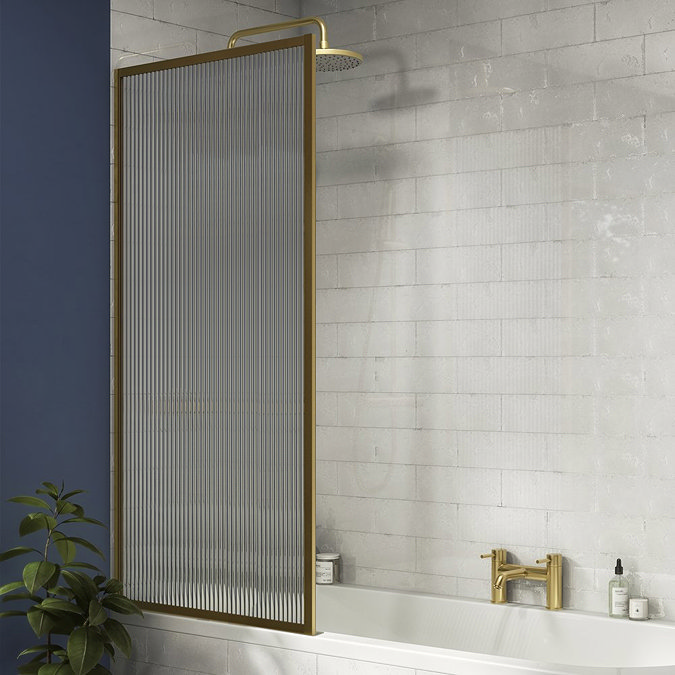 Modern bathroom with a ribbed glass shower screen framed in brushed brass, textured white wall tiles, navy blue feature wall, and brass taps, creating a boutique, spa-like aesthetic.