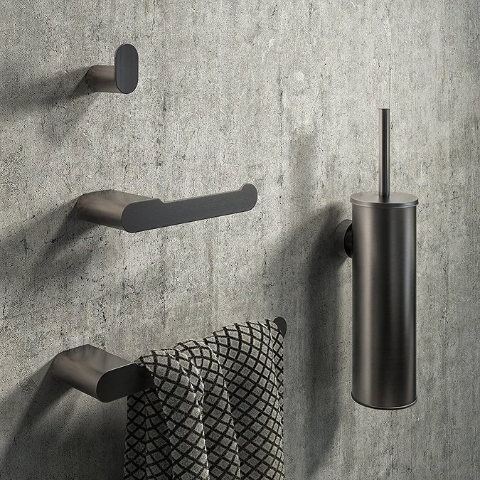 Modern black matte toilet roll holder and bathroom accessories set against a concrete-textured wall, featuring sleek, minimalist design elements, including a towel rail and toilet brush holder.