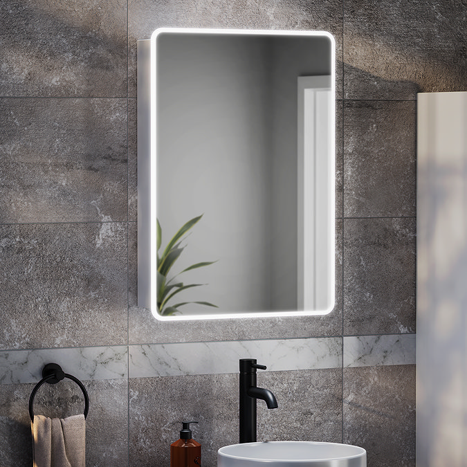 Toreno backlit LED bathroom mirror with rounded corners, mounted above a modern countertop basin and matt black tap on grey stone-effect tiles.