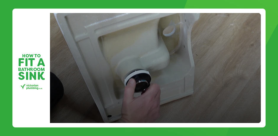 Tightening basin waste nut underneath a bathroom sink during installation
