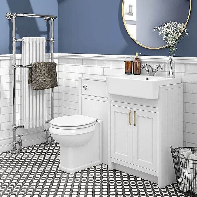 Traditional-style bathroom with a white combination unit featuring a back-to-wall toilet and vanity basin. The space includes a chrome heated towel rail, blue walls, white metro tiles, and patterned black-and-white flooring.