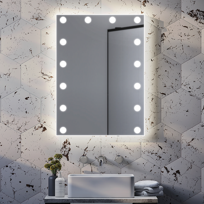 Hollywood-style illuminated bathroom mirror with round LED lights, mounted on a hexagonal marble-effect tiled wall, above a modern countertop basin and minimalist tap.