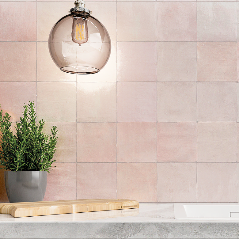 Soft pink handcrafted-look square tiles behind kitchen counter.