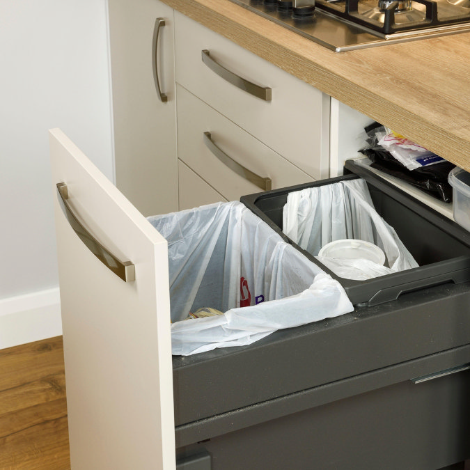 Modern kitchen pull-out bin drawer with two compartments for rubbish and recycling under wooden countertop