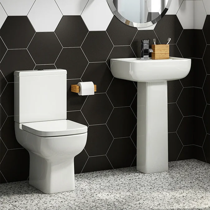 Modern bathroom with white close-coupled toilet and pedestal basin, set against bold black and white hexagonal wall tiles, and terrazzo flooring for a sleek contemporary look.