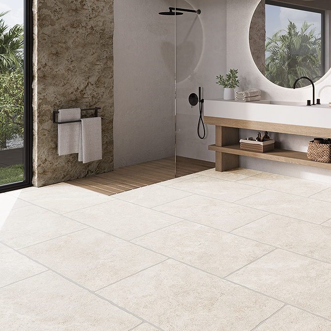 Contemporary bathroom with large beige stone-effect tiles, a walk-in shower, wooden vanity, and minimalist black fixtures, blending natural textures for a modern, earthy aesthetic.