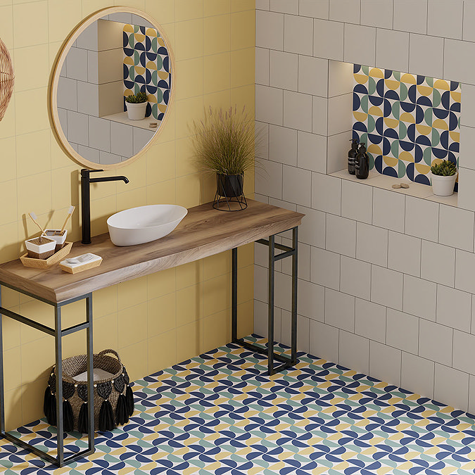 Bathroom with a wooden vanity and round mirror, featuring retro-style geometric floor tiles in blue, yellow, and white. Yellow accent wall and niche with matching patterned tiles, creating a bright and playful design.