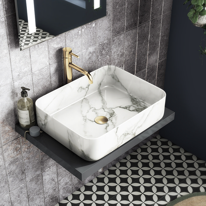 Marble rectangular sink with gold tap and patterned tile flooring in a modern bathroom