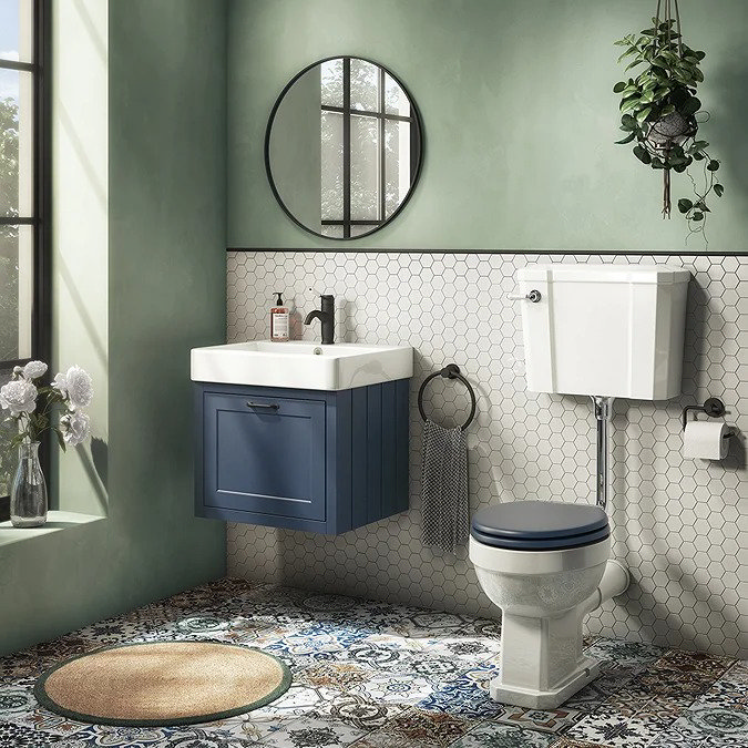 Vintage-style bathroom with a navy blue vanity, hexagonal white tile backsplash, patterned floor tiles, and a traditional high-level toilet.