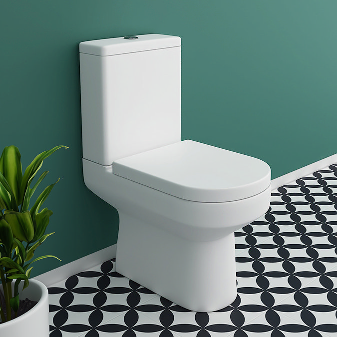 Contemporary close-coupled toilet with a modern design against a teal wall and geometric tiled floor, next to a potted plant.