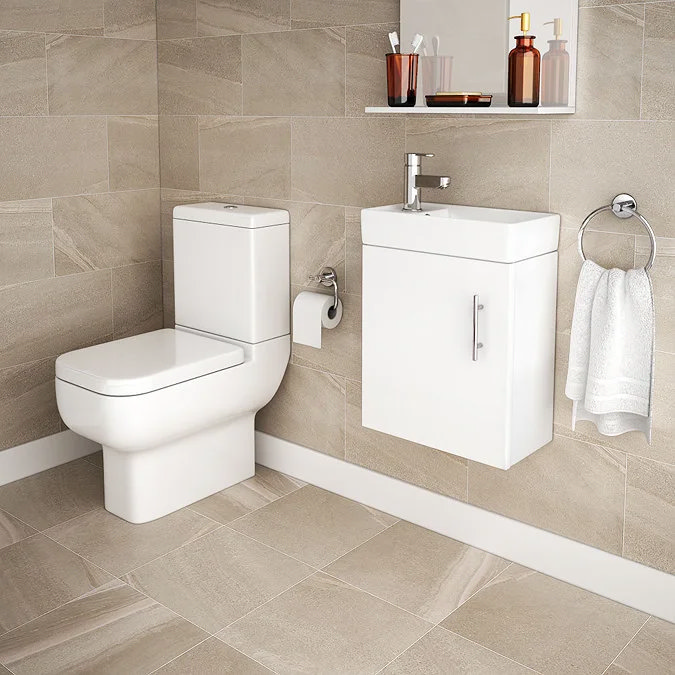 Compact bathroom with beige tiled walls and a white modern toilet paired with a sleek wall-mounted vanity unit. Minimalist design maximises space, while warm tones create a calming atmosphere.