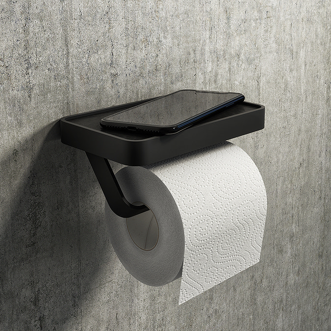 Black toilet roll holder with a phone shelf mounted on a grey concrete wall