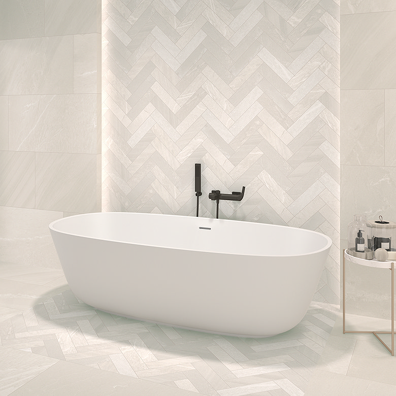 Light stone herringbone tiles behind freestanding bath in spa bathroom.