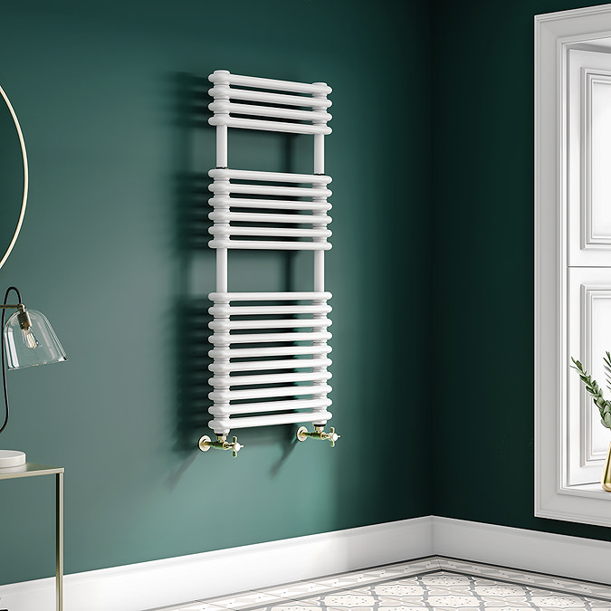 White heated towel rail against dark green bathroom wall with patterned floor tiles