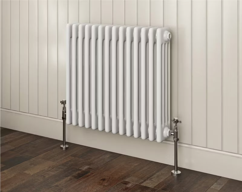 White traditional column radiator against cream panelled wall with dark wood flooring