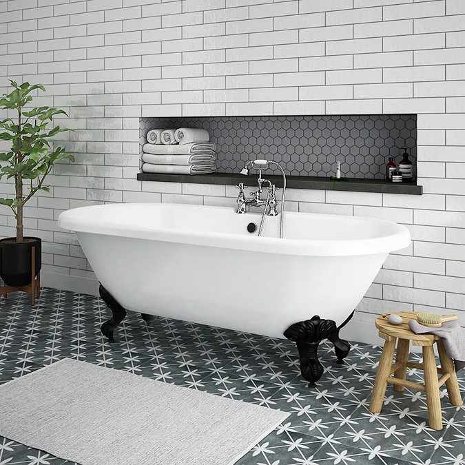 Freestanding white clawfoot bathtub with black legs, subway tiles, and patterned floor