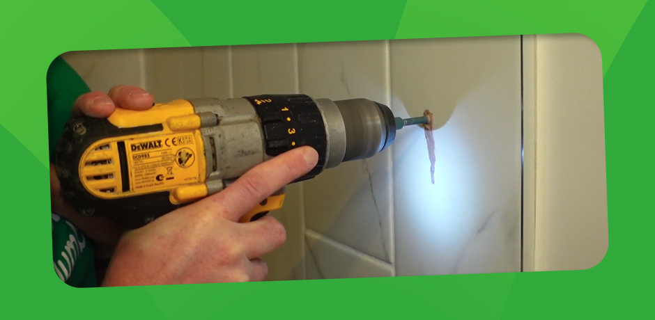 Close-up of a DeWalt drill with a diamond bit in use, creating a clean hole in a bathroom tile under proper lighting.