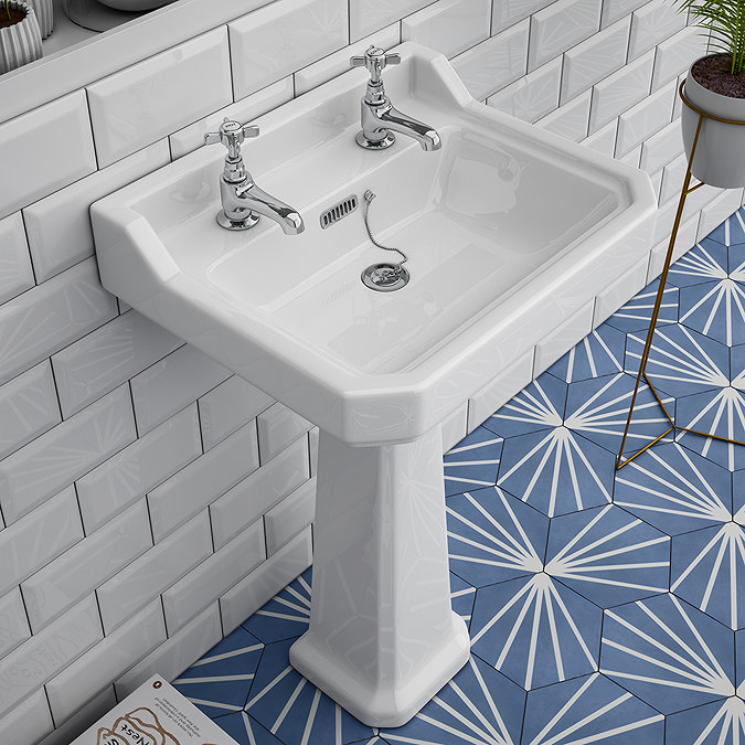 White pedestal sink with chrome taps and geometric blue floor tiles