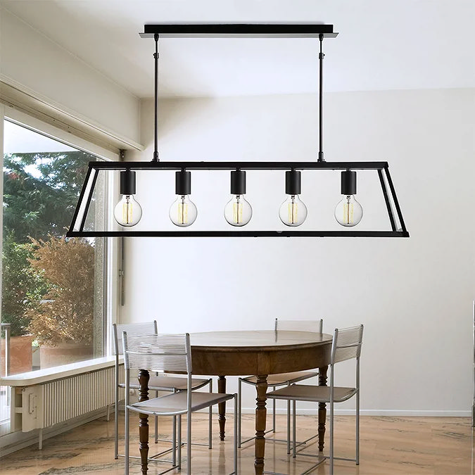 Modern industrial-style pendant light with a black metal frame and five exposed Edison-style bulbs, positioned above a wooden dining table in a bright, minimalist dining room.