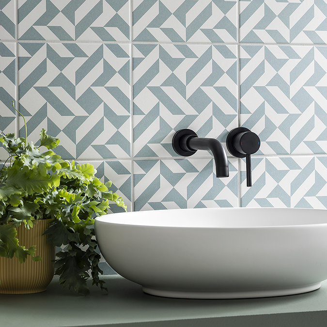 Eye-catching geometric feature wall tiles in soft blue and white add a modern, playful vibe to the bathroom, creating a striking contrast with the matte black fixtures.