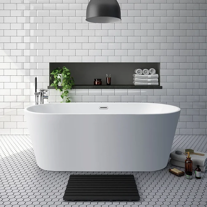 Freestanding white bathtub with hexagonal floor tiles and a shelf holding towels and plants